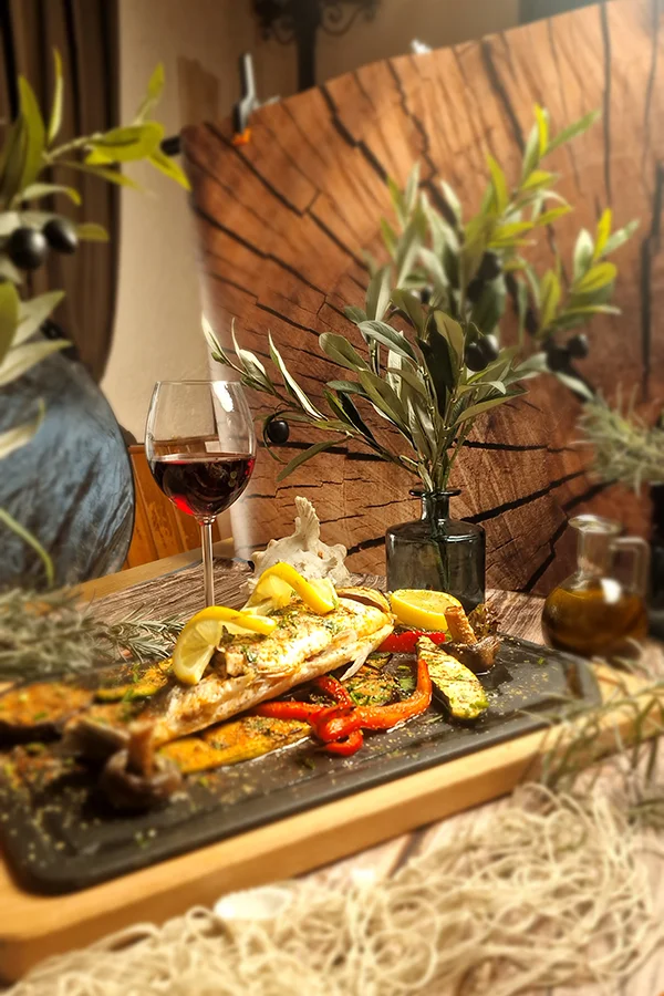 Dekorierter Teller mit Fisch und einem Glas Wein daneben