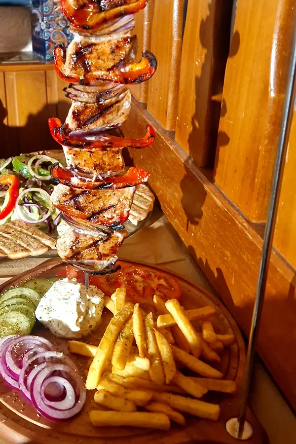 Fleisch mit Paprika und Zwiebeln auf einem Spieß mit Pommes und Tsatsiki